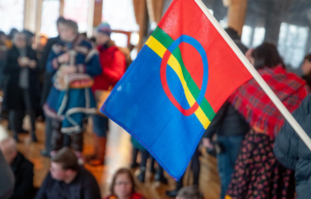 Sami flag and people indoors.