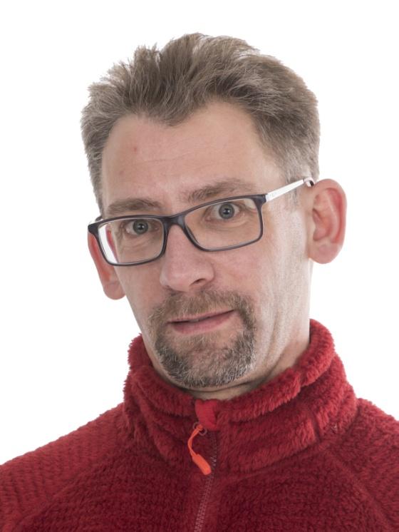 portrett av ein mann med briller og raud genser