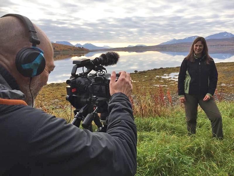 Man filming woman in coastal landscape, Northern Norway