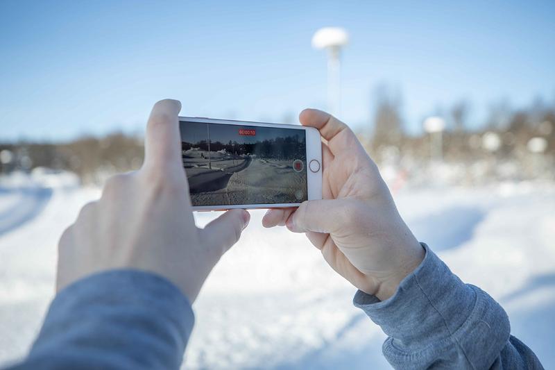 Hender som holder en mobil og filmer vinterlandskap