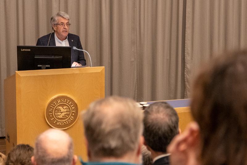 historie50år-221201-4.jpg Ein mann snakkar til folk i eit auditorium