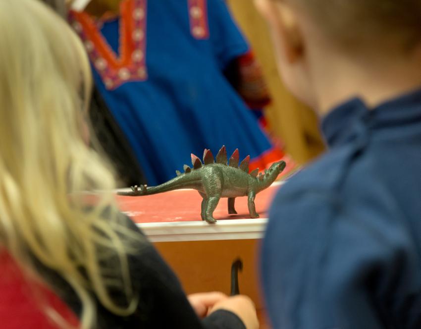 barn som ser p&aring; en lekedinosaur 