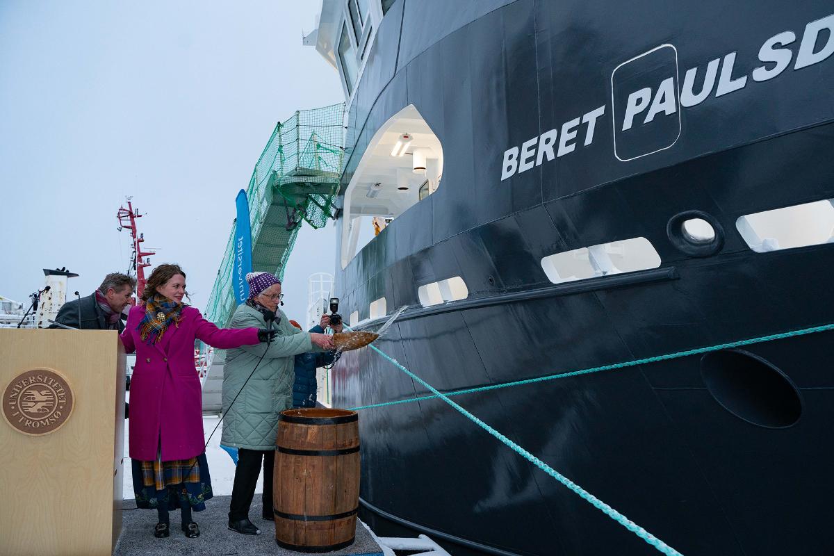 Tre personer foran en b&aring;t ved kai