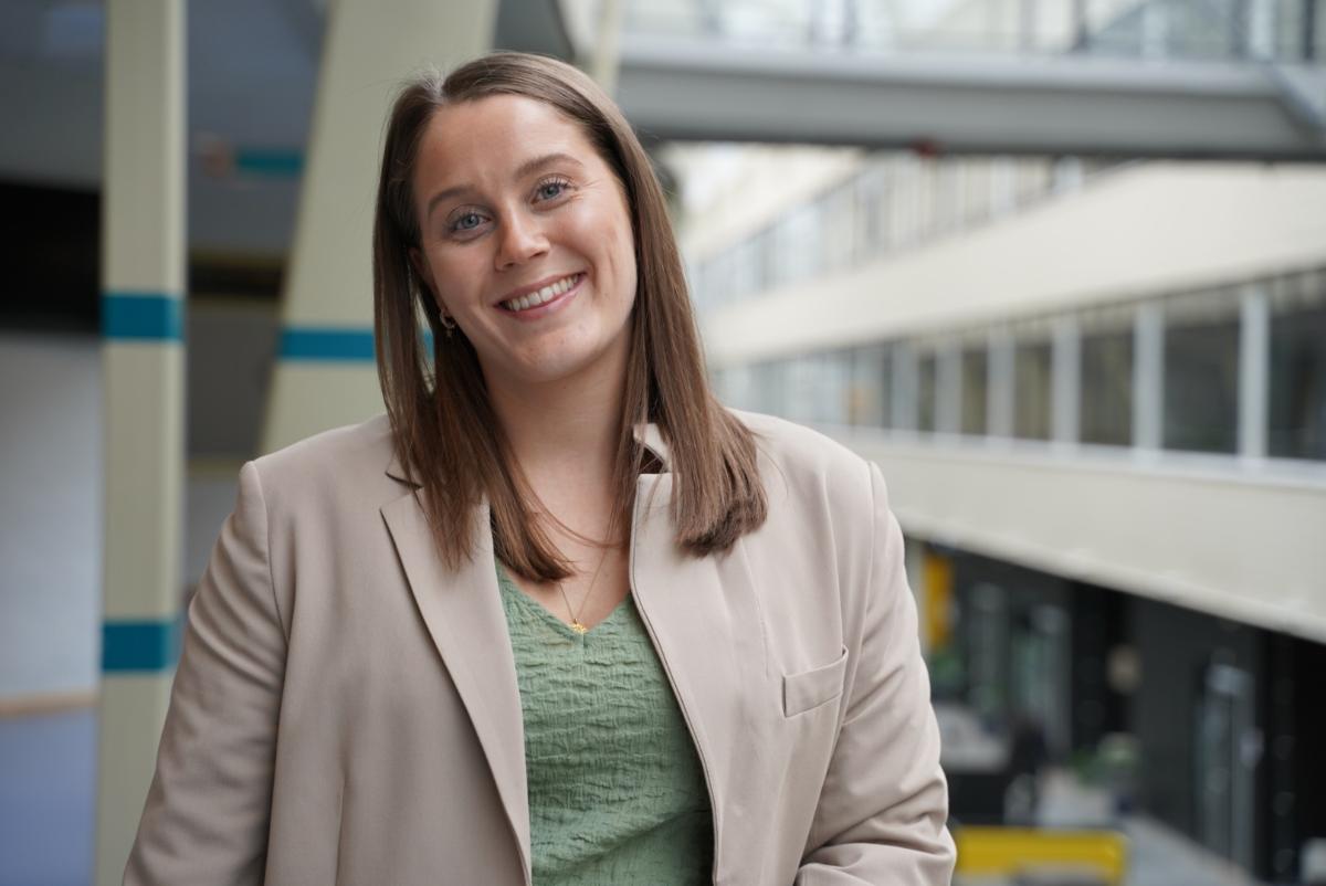 Dame lener mot rekkverk, smiler til fotograf