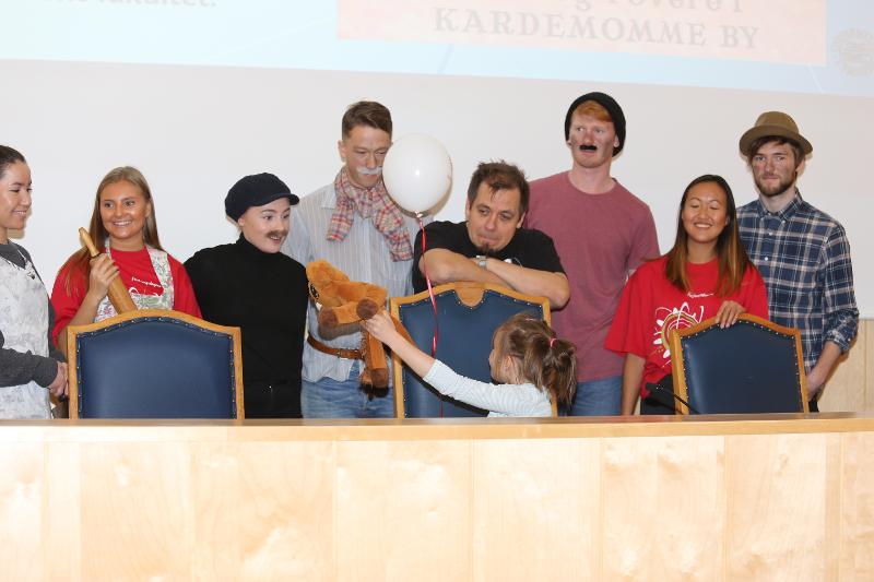 EIn rekkje menneske, nokre i kostymar, i noko som ser ut som ein jurybenk.