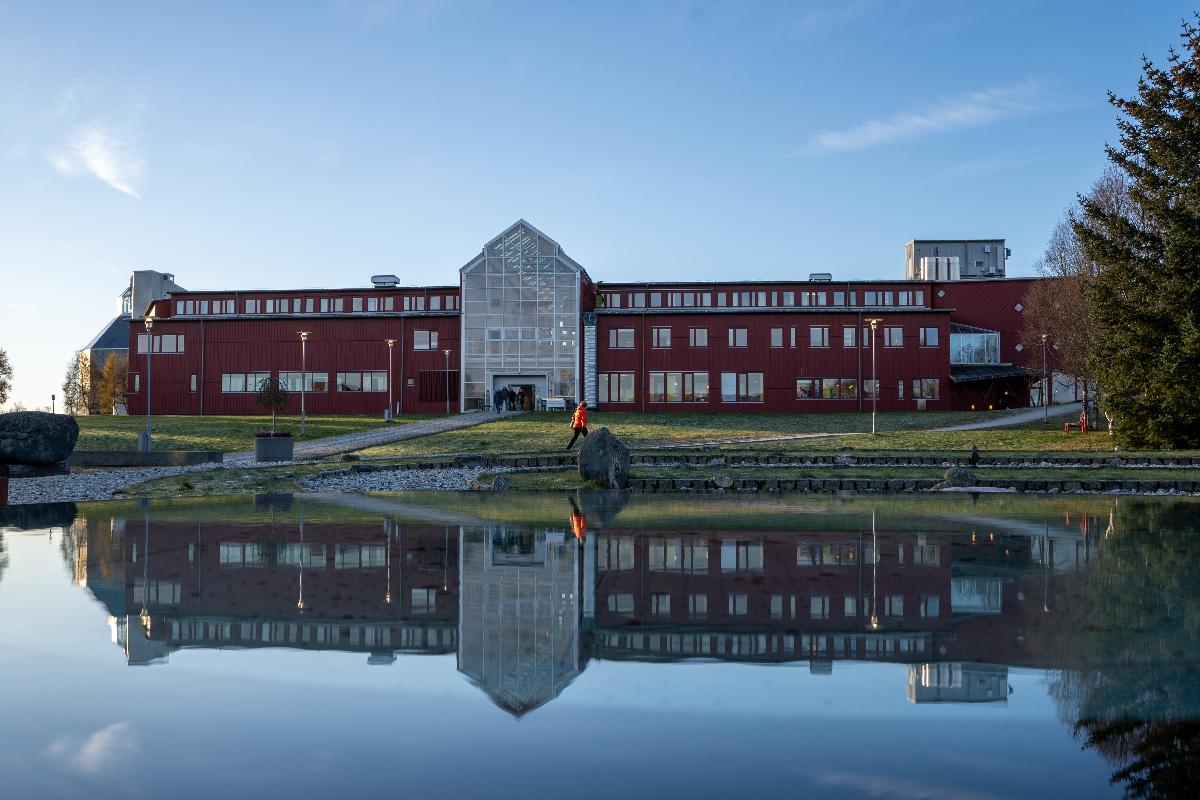 Rødt administrasjonsbygg reflektert i vann