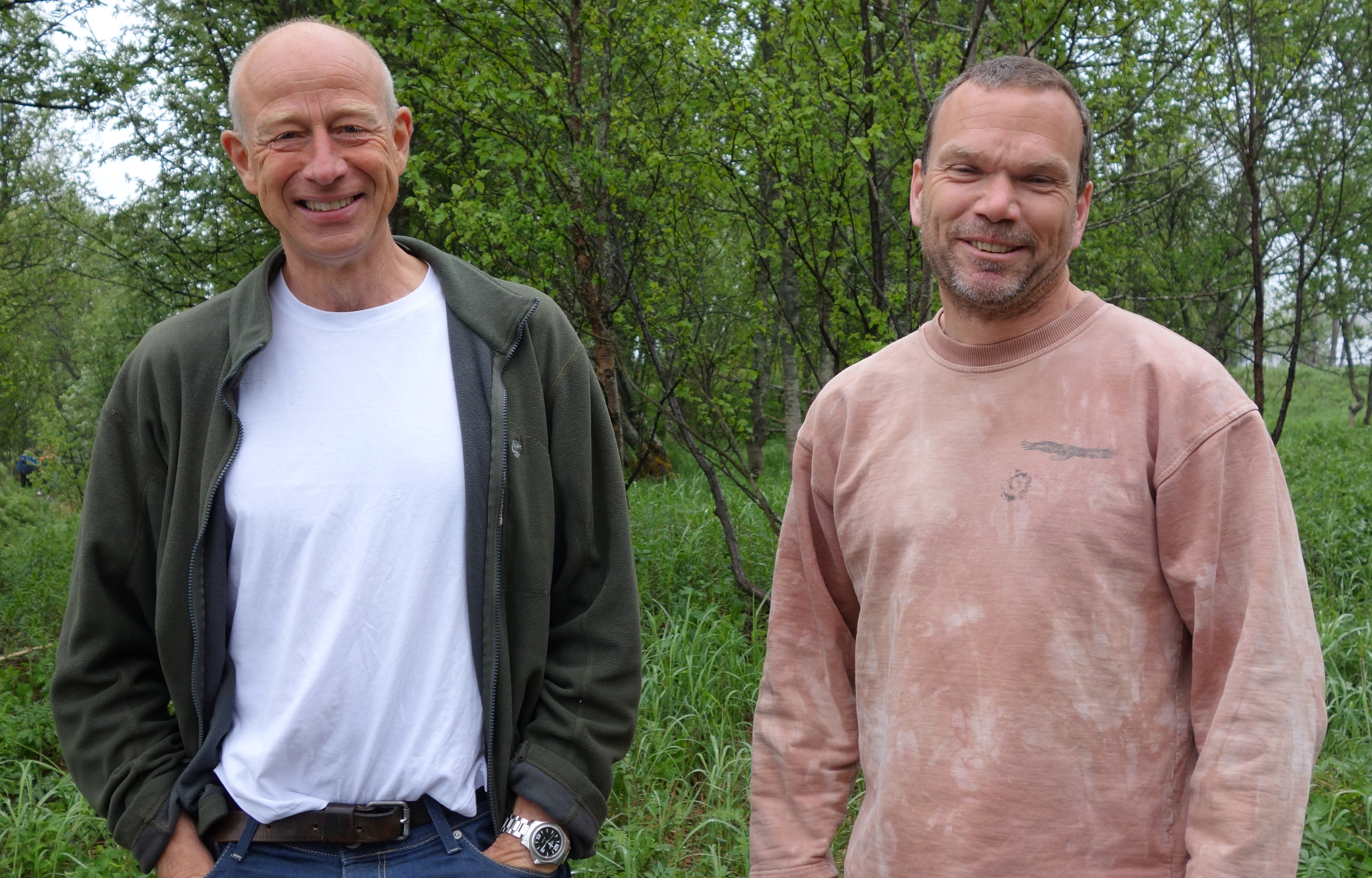 to forskere som står ute foran skog og smiler