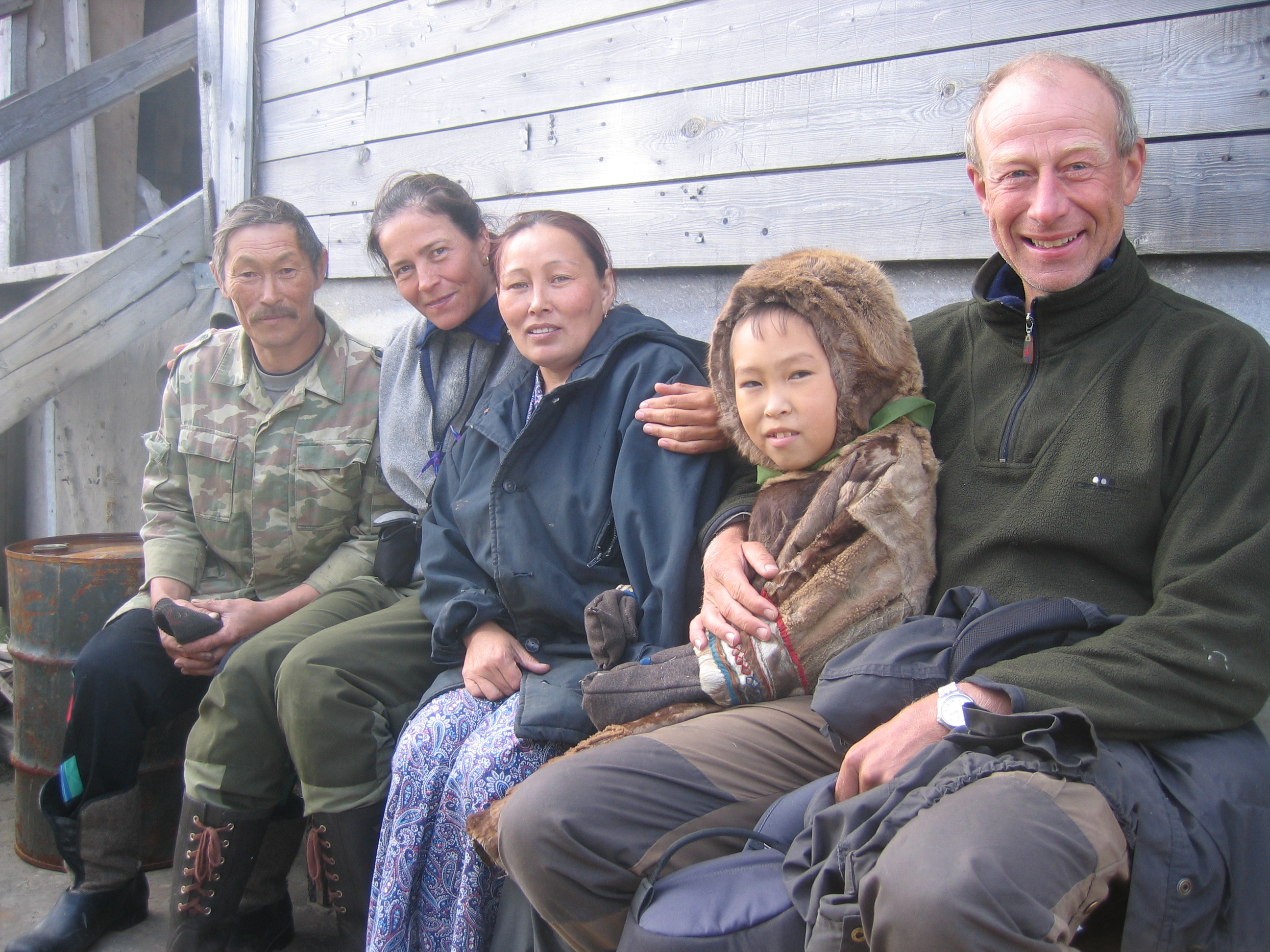 to forskere sammen med en familie med russisk urbefolkning som sitter på en benk
