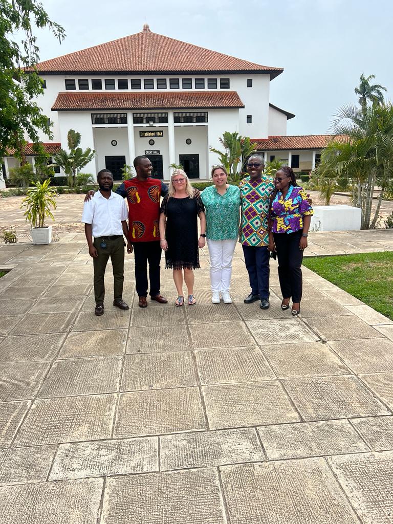 Christin Skjervold and Maria Das Neves standing in front of great hall in Ghana with other people