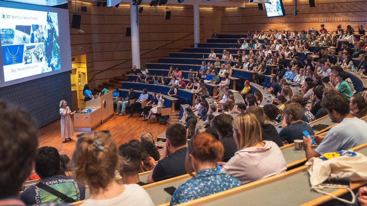 Person holding a speech before an audience in an audiotorium.