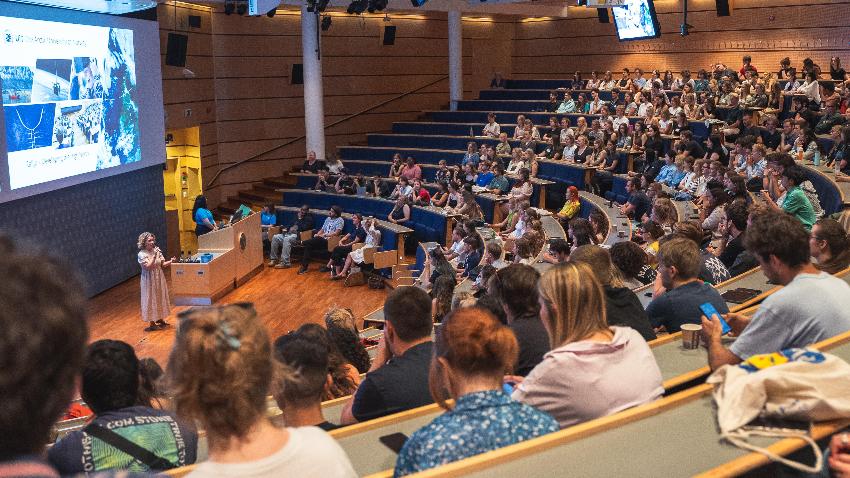 Person holding a speech before an audience in an audiotorium.