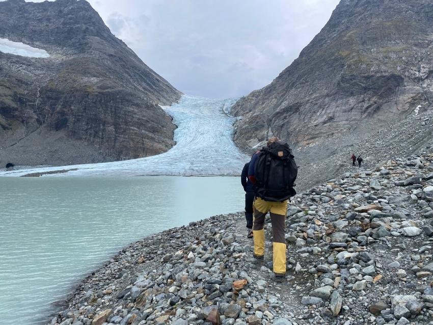 People walking in the mountains, towards a glacier.