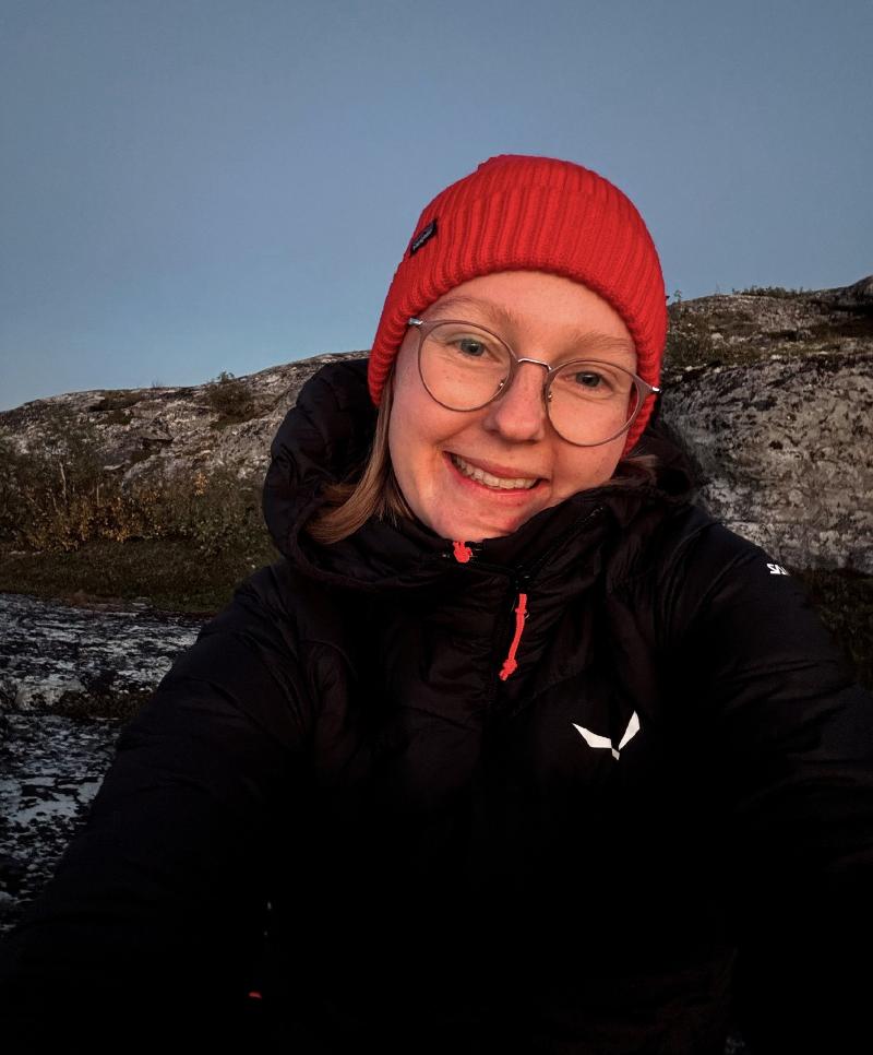 Woman wearing a red cap in an Arctic landscape.