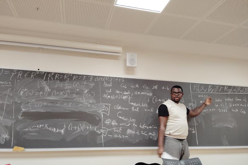 Person standing by a black board.