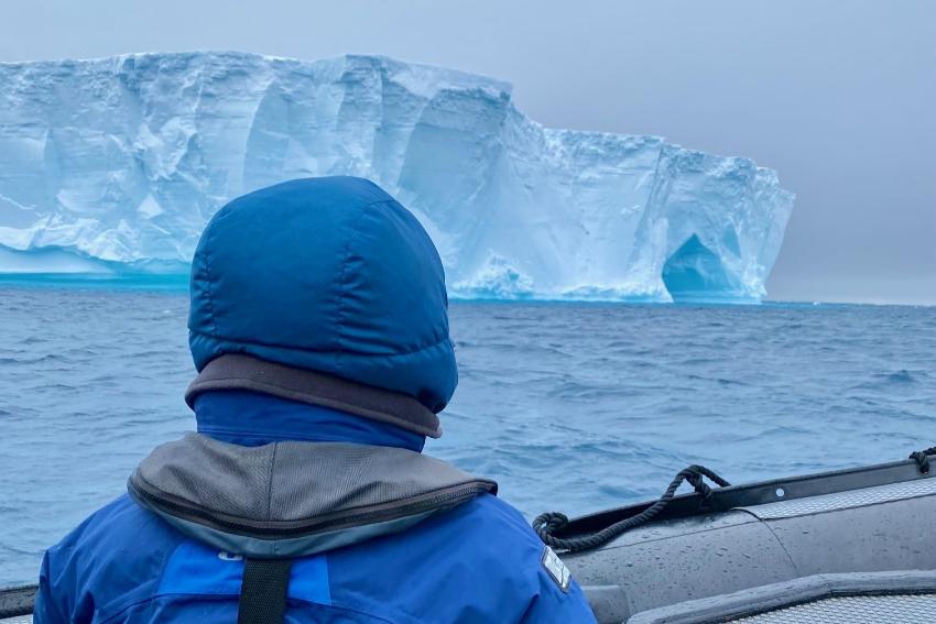 a person in a rib boat looking at an enormous ice berg