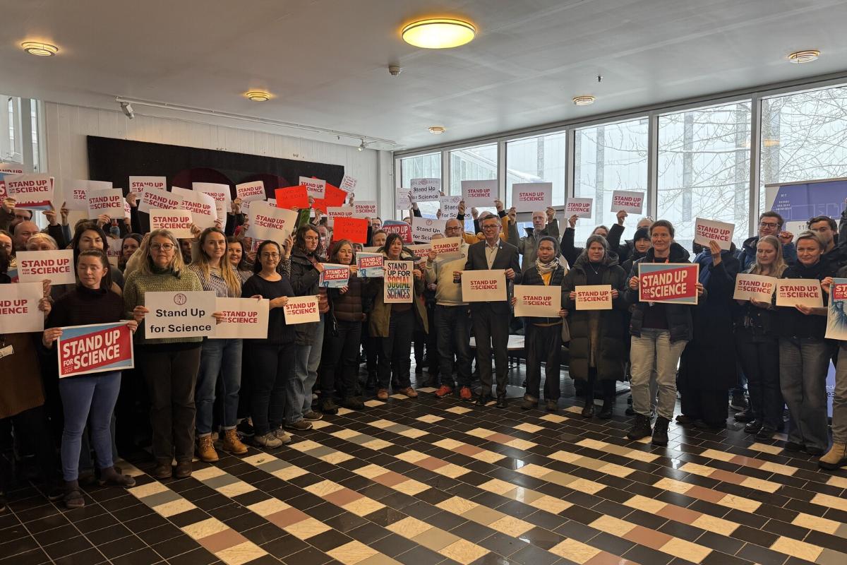 Personer som st&aring;r p&aring; linje og holder plakater