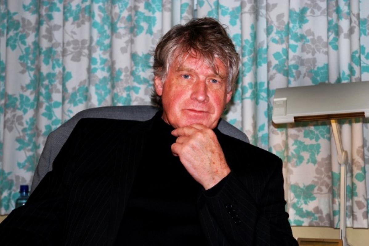 En mann poserer sittende p&aring; et kontor