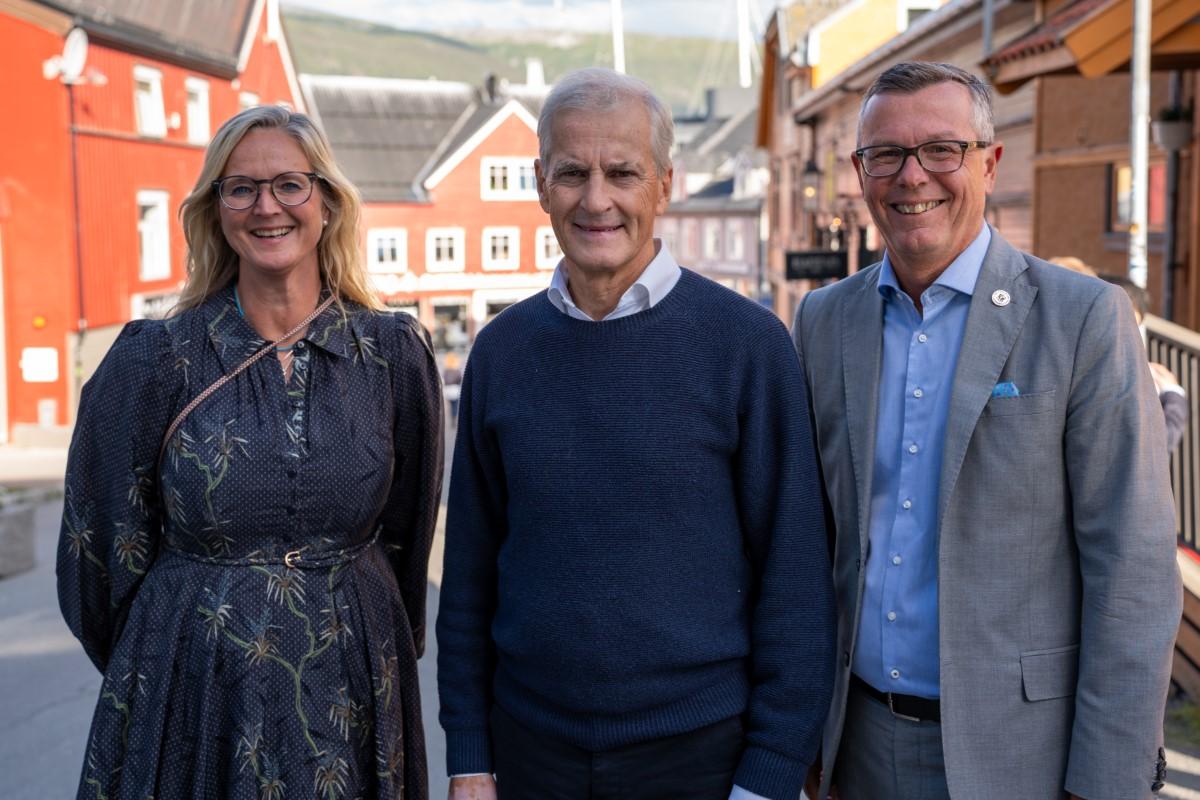 en kvinne og to menn poserer på gaten i en by