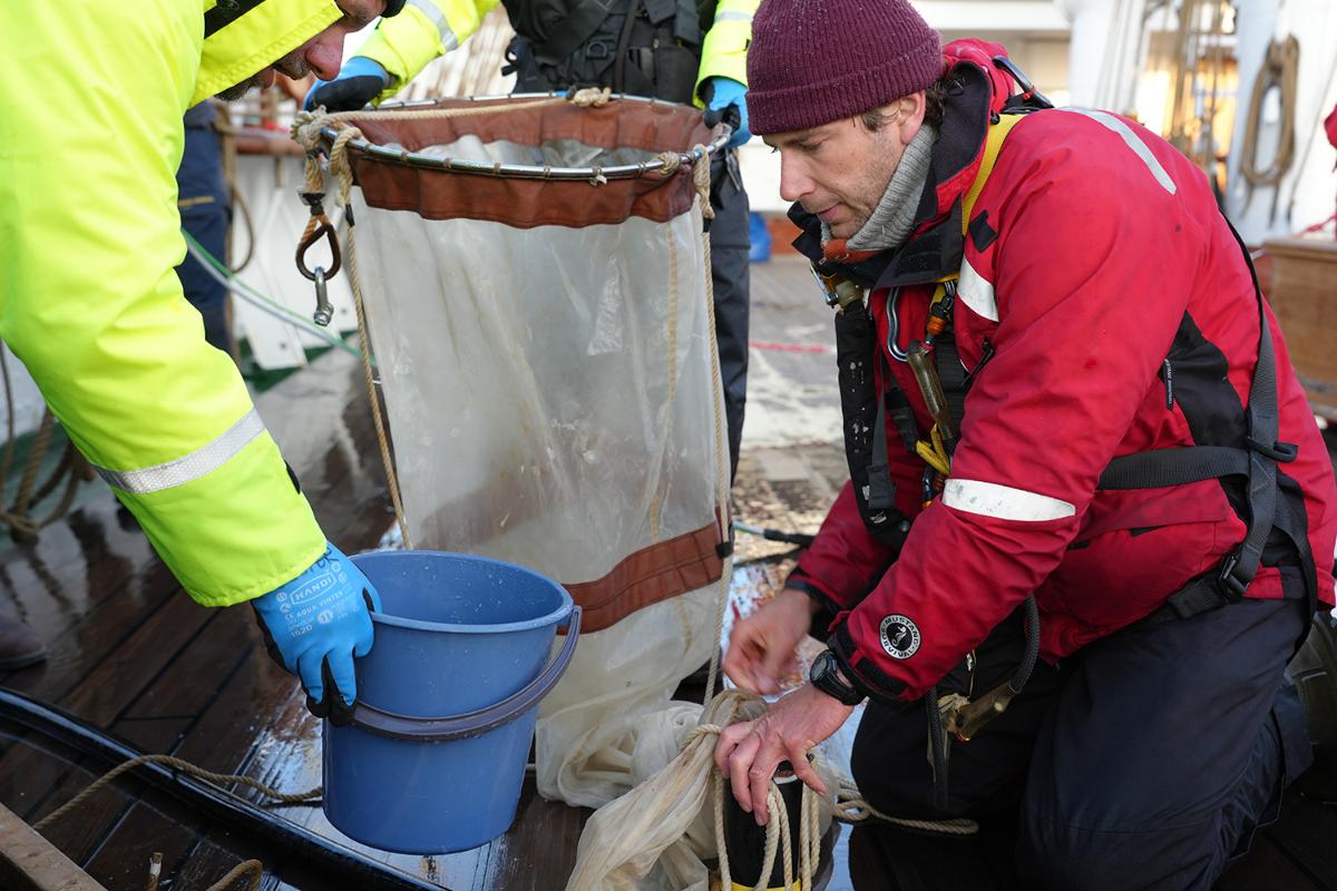 A man sits on deck and rinse equipment