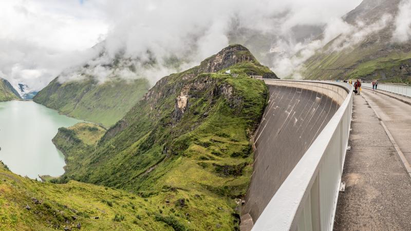 Photo of a hydropower dam surrounded by forests and mountains.