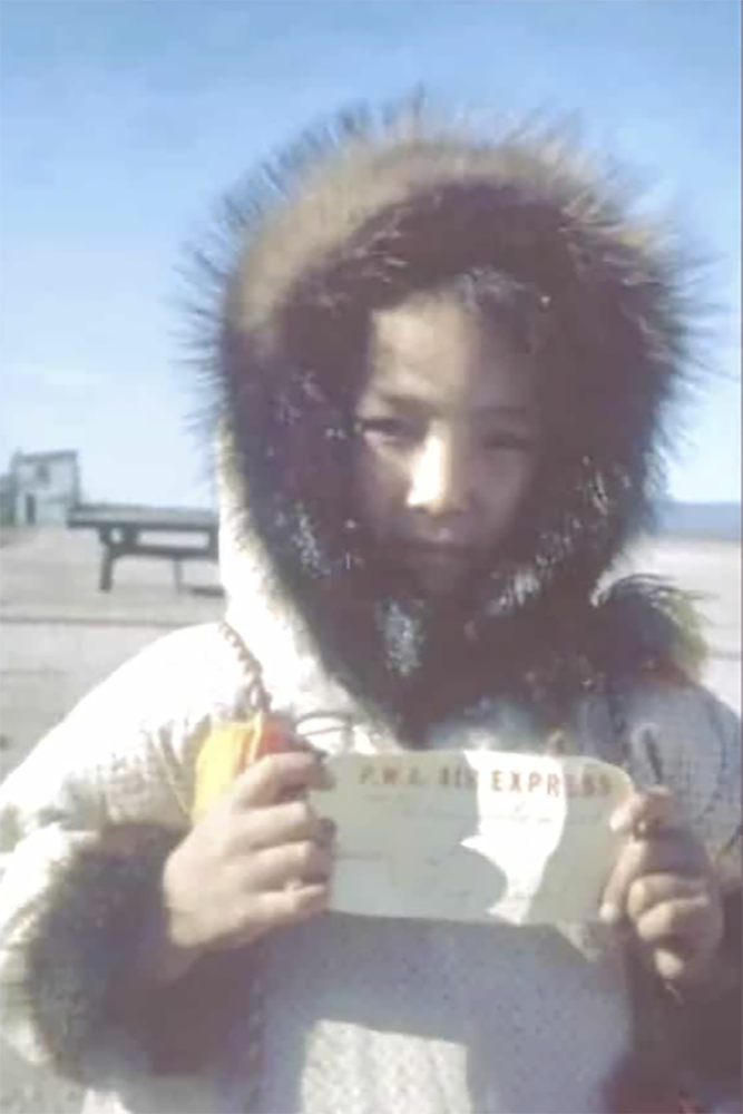Inuk child holding a flight ticket.