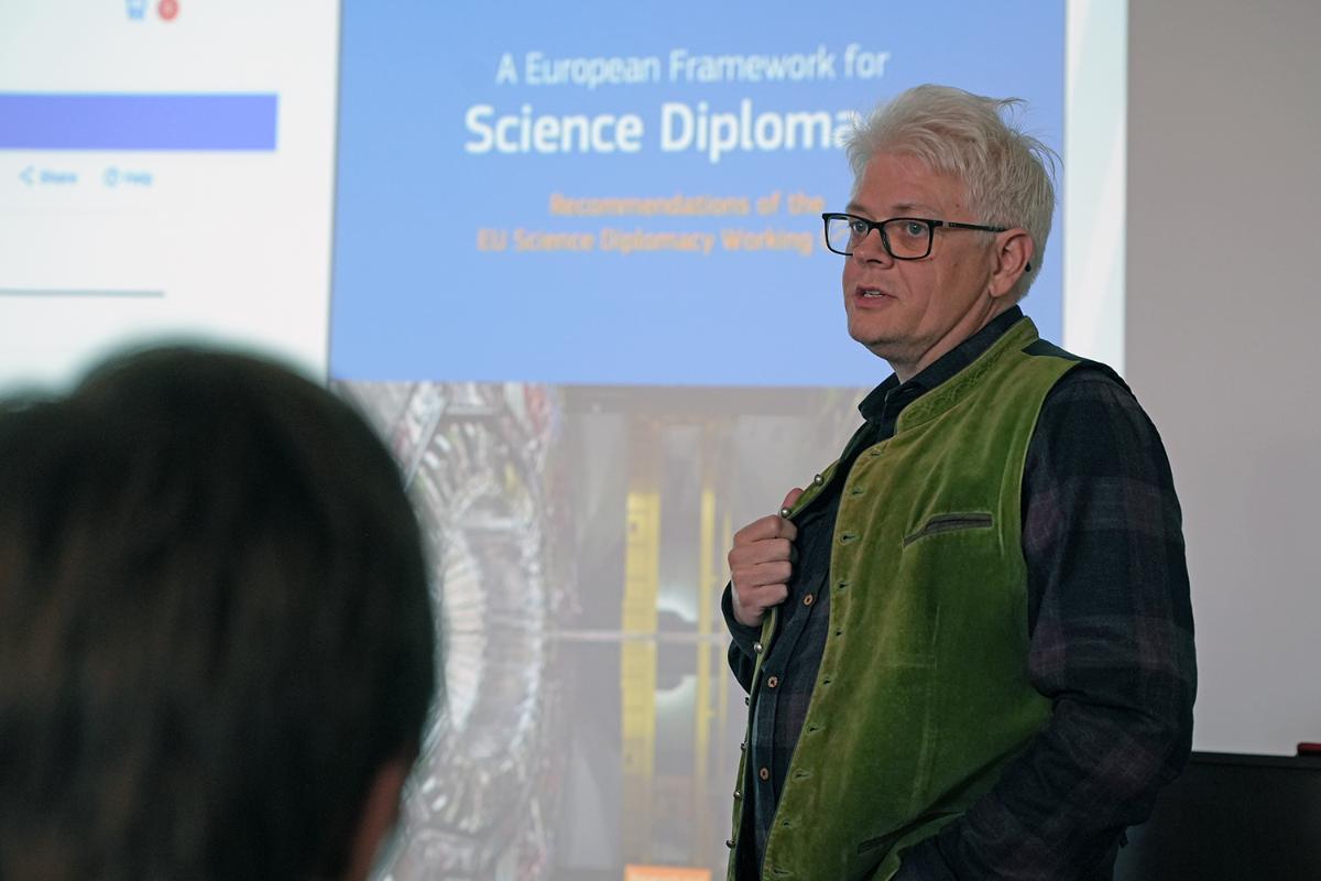 Person står og snakker foran et bilde