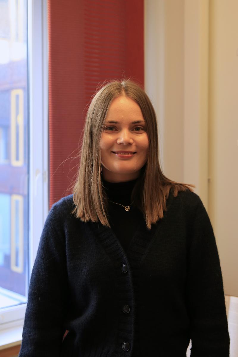 Jente med brunt hår smiler til kamera.