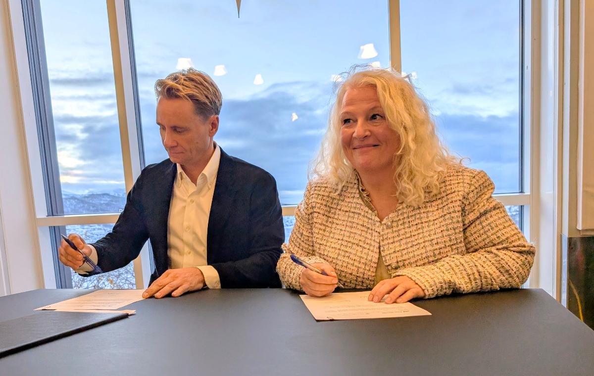 To personer sitter evd bord og signerer p&aring; avtale