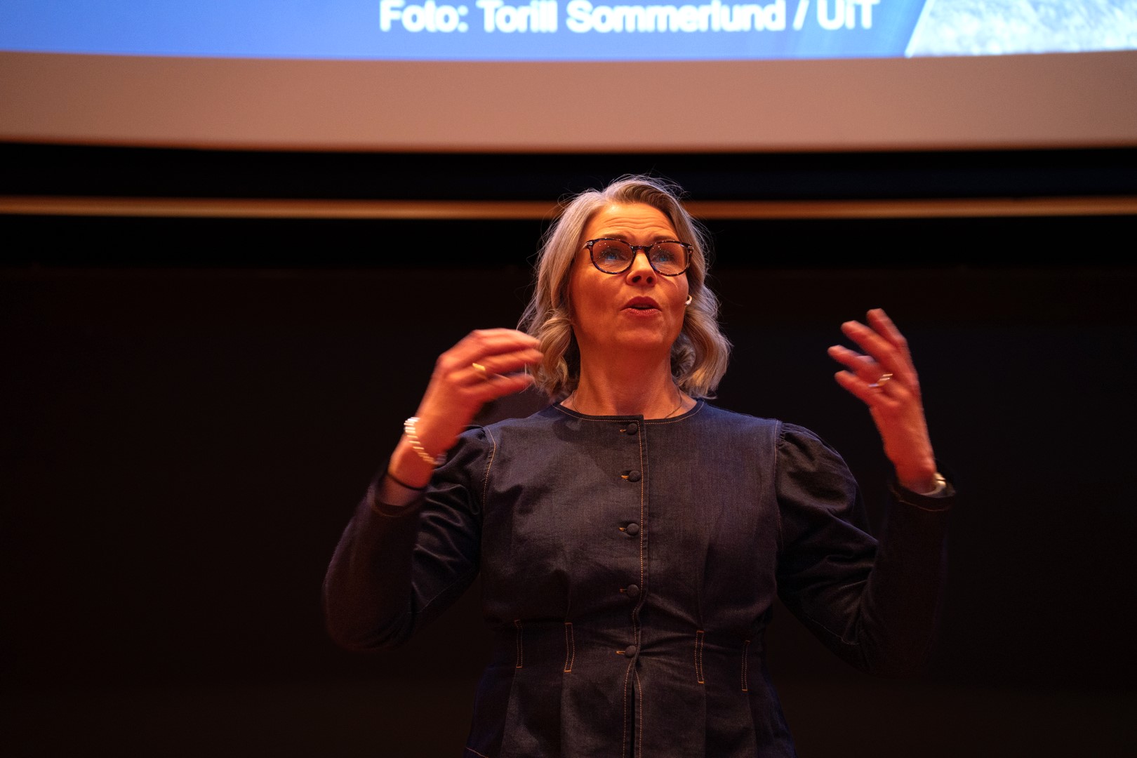 Kvinne taler engasjert til forsamling. 