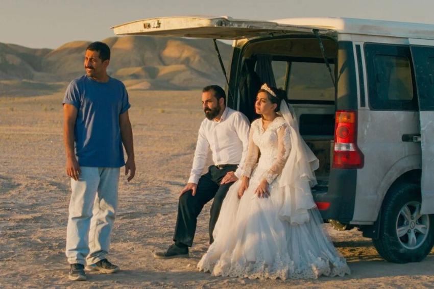 People gathered around a van, in the desert
