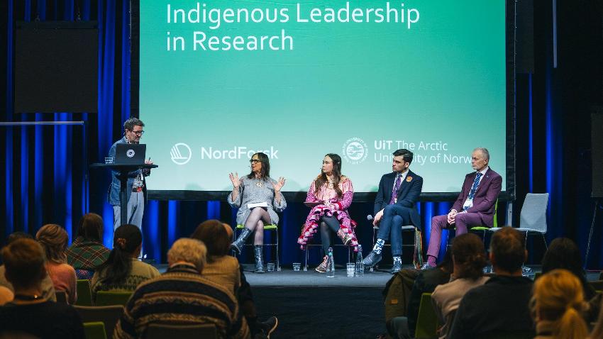 People sitting on a stage during a conference.