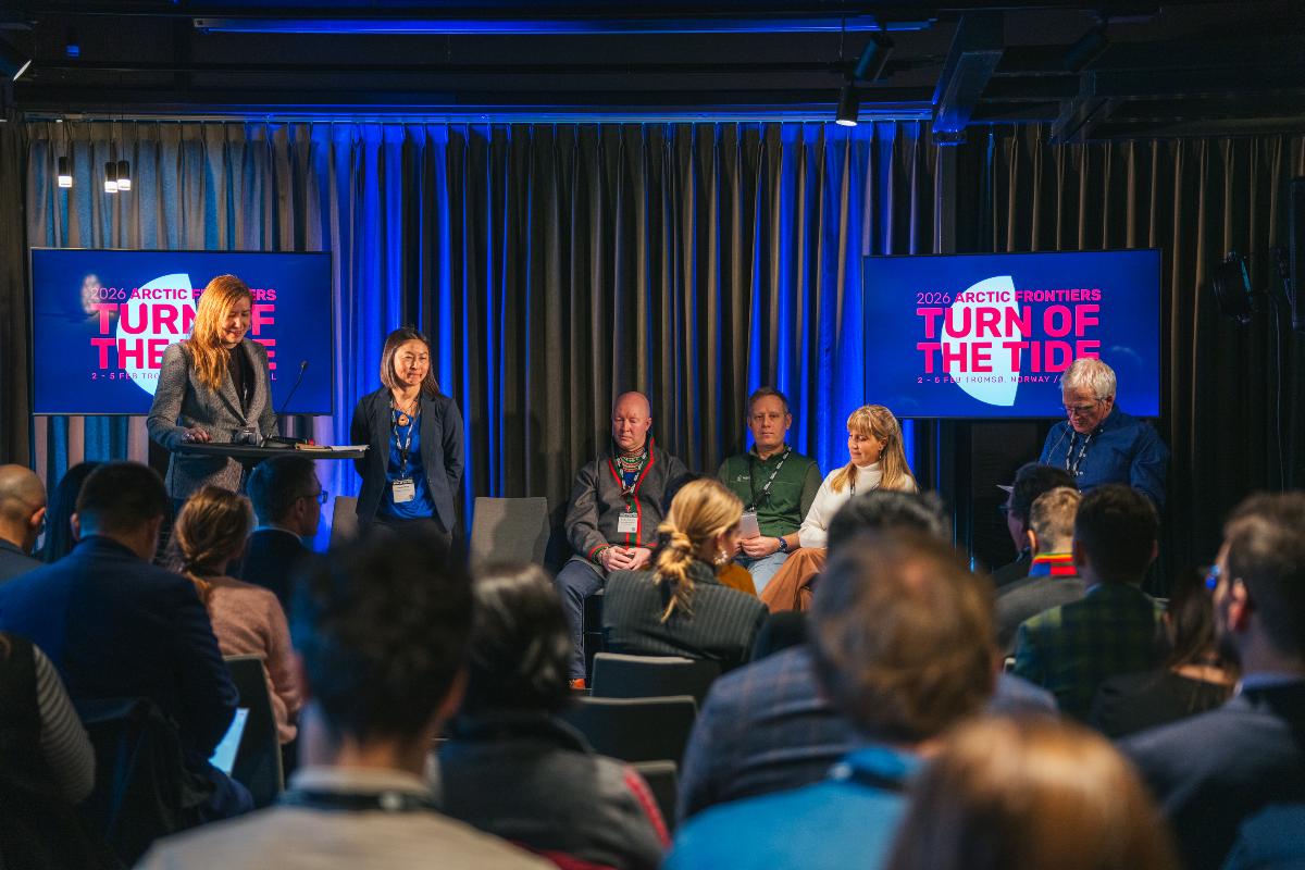 Flere personer sitter p&aring; en scene.