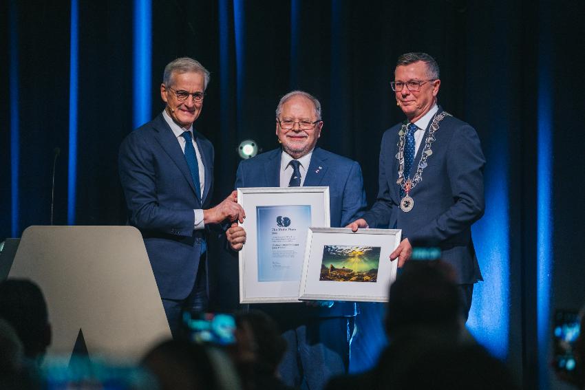 Three happy men with a diploma on a stage