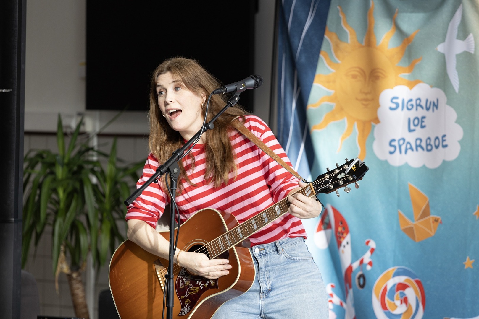 Bursdag6.jpg Kvinne spiller gitar på scene.