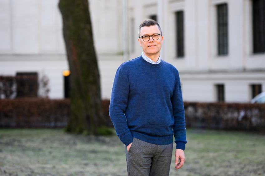 mann, kort h&aring;r, briller, ser i kamera, st&aring;r ute med h&aring;nd i lomma