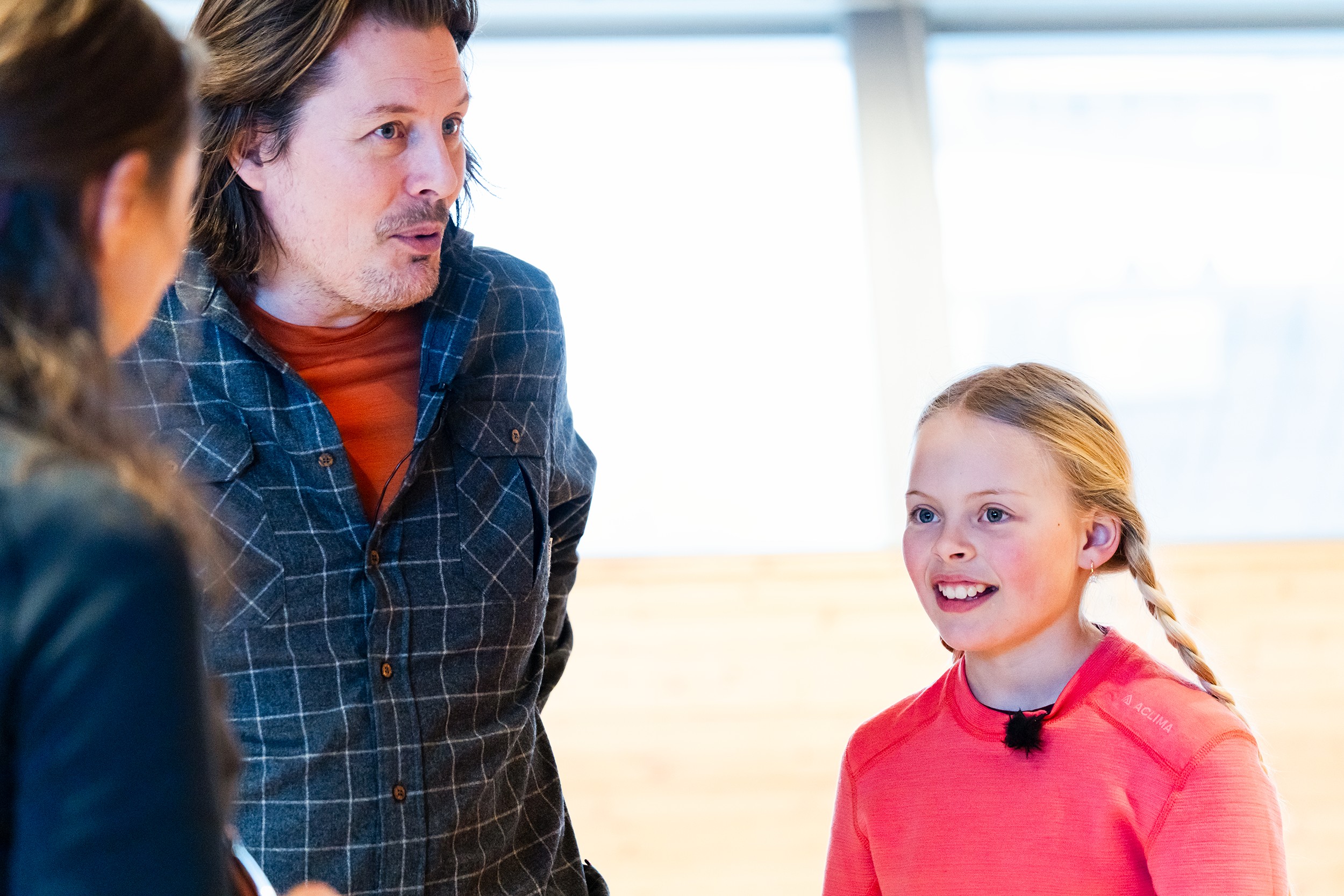 en mann og en dame som snakker med ei jente medd lange fletter