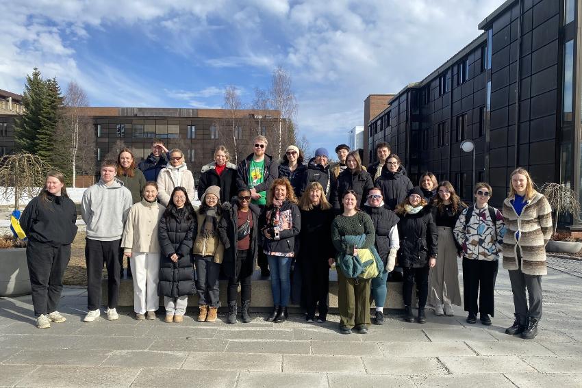 People standing in two lines, outdoors, with office buildings behind.