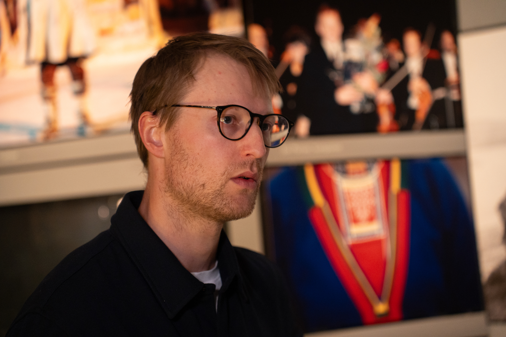 Forsker foran bilder med samiske symboler. 