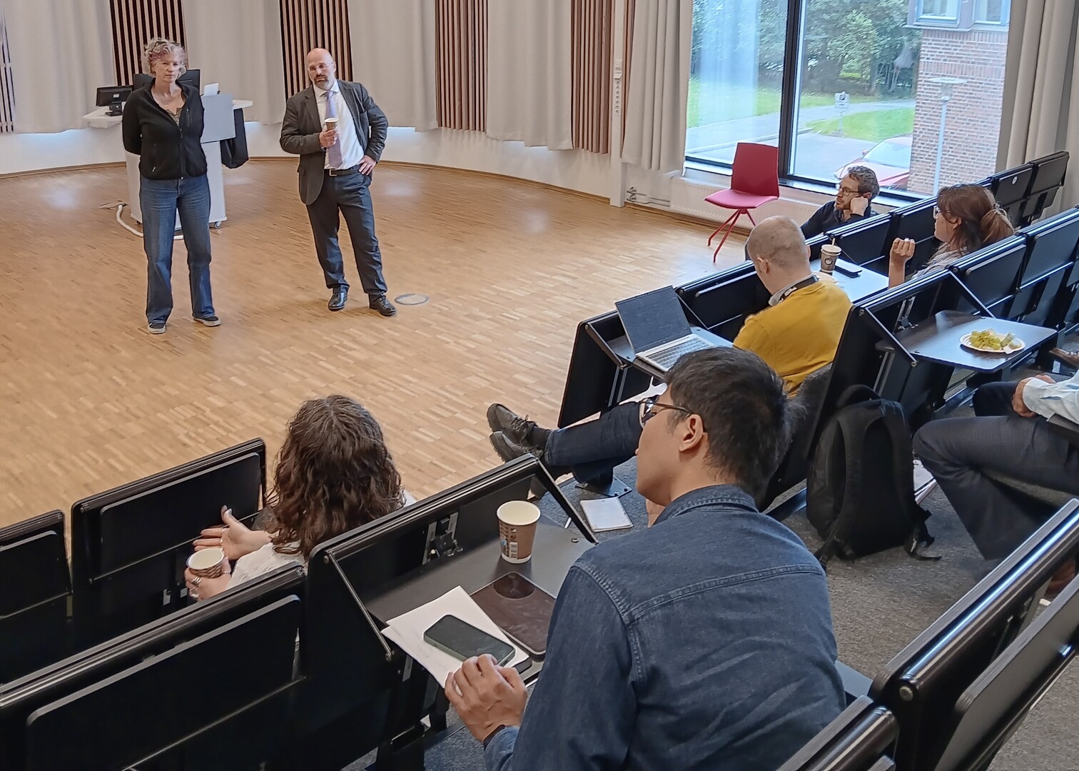 To forskere st&aring;r foran publikum i et audiotorium.