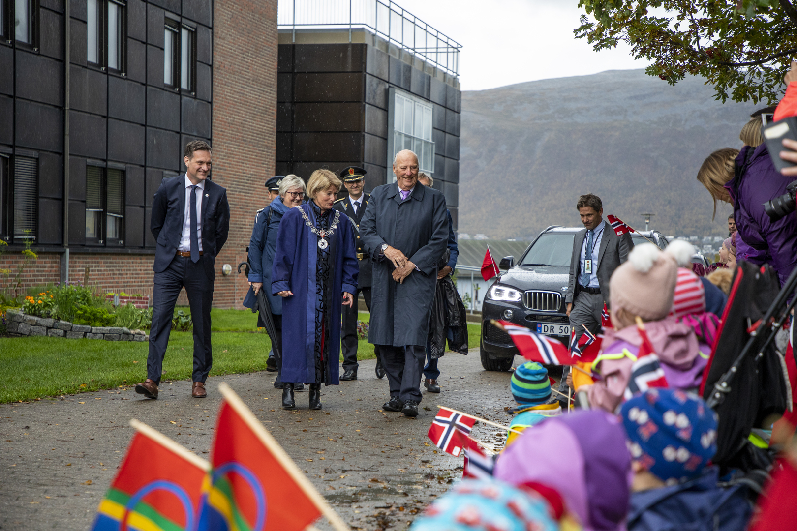 King walking together with other leaders while kids are waving flags