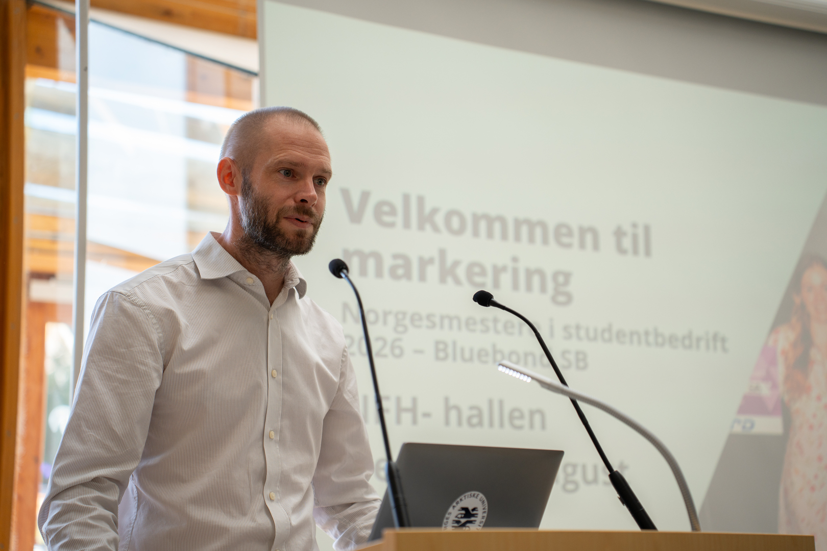 Mannlig dekan p&aring; talerstol i universitetsbygg. 