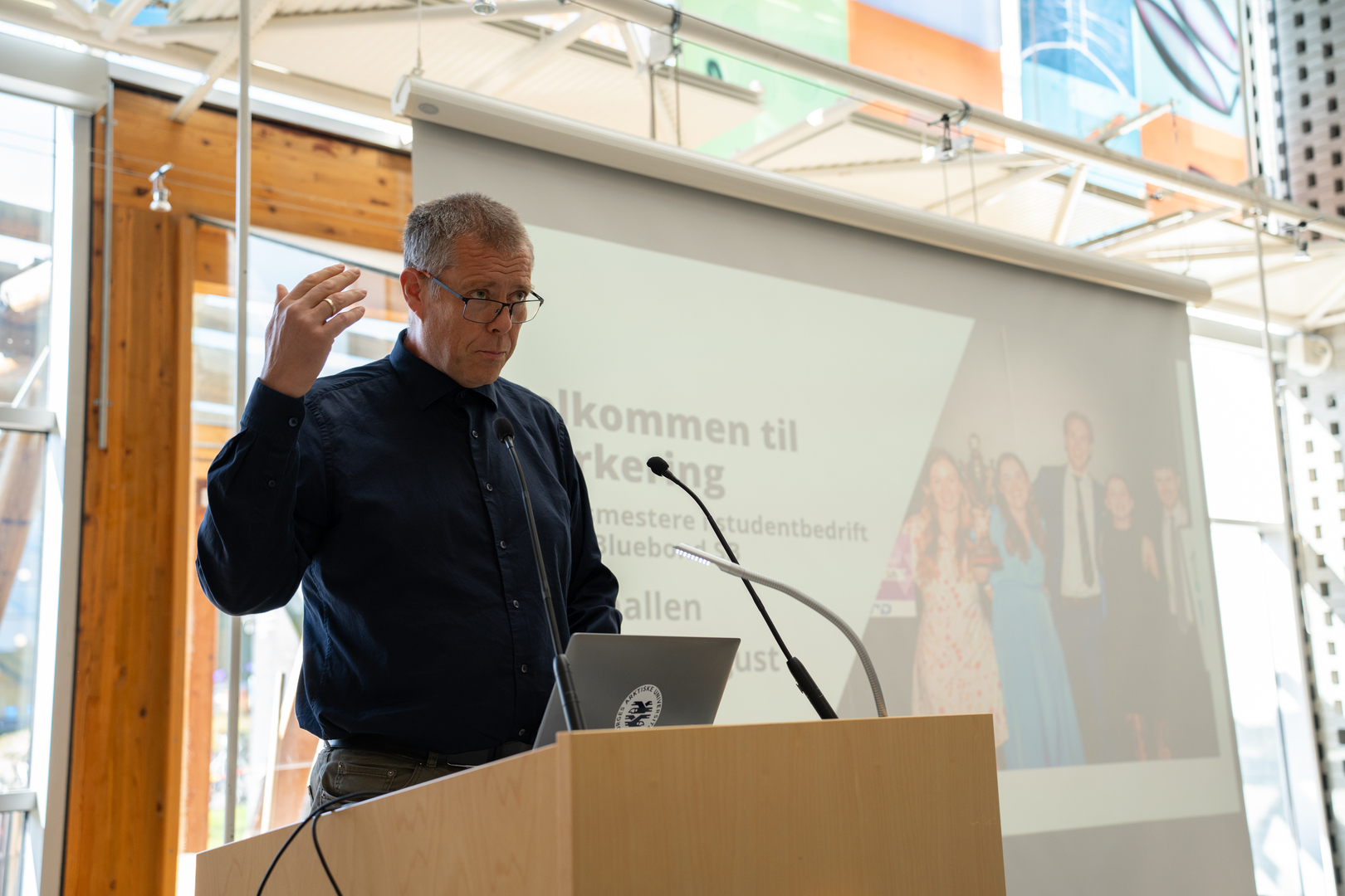Mann, prorektor, p&aring; talerstol i universitetsbygning.