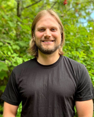 Jan Viljanen 2.jpg Portrettfoto av mann med løvskog bak