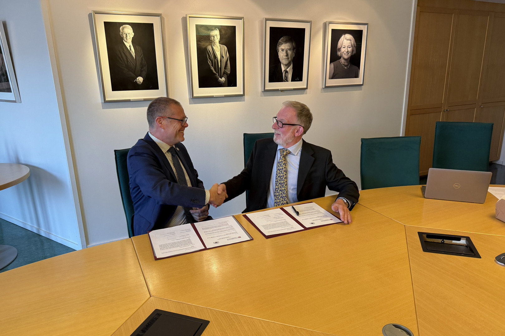 To personer ved et bord som gir hverandre et h&aring;ndtrykk.