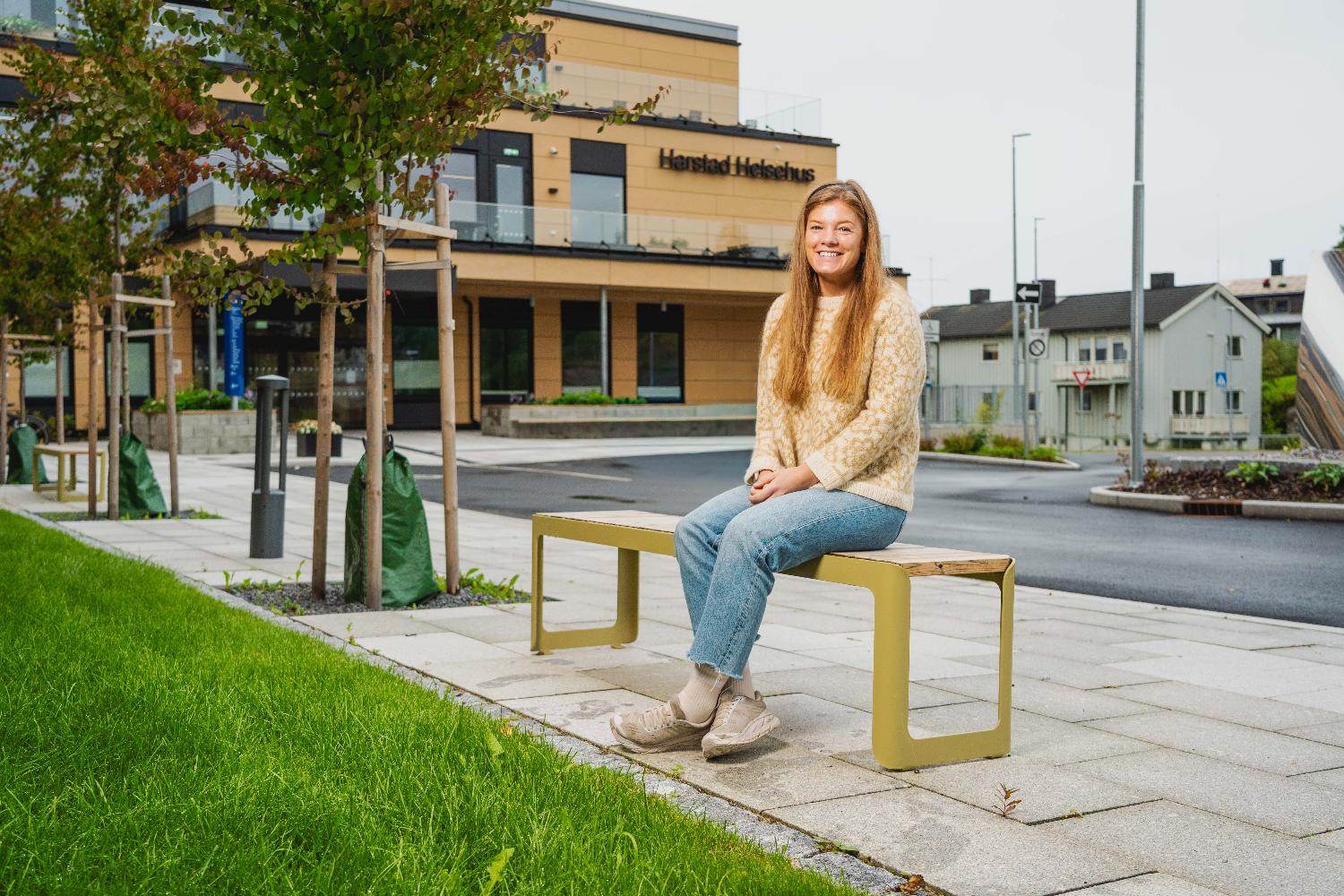  En person sitter på benk foran en bygning